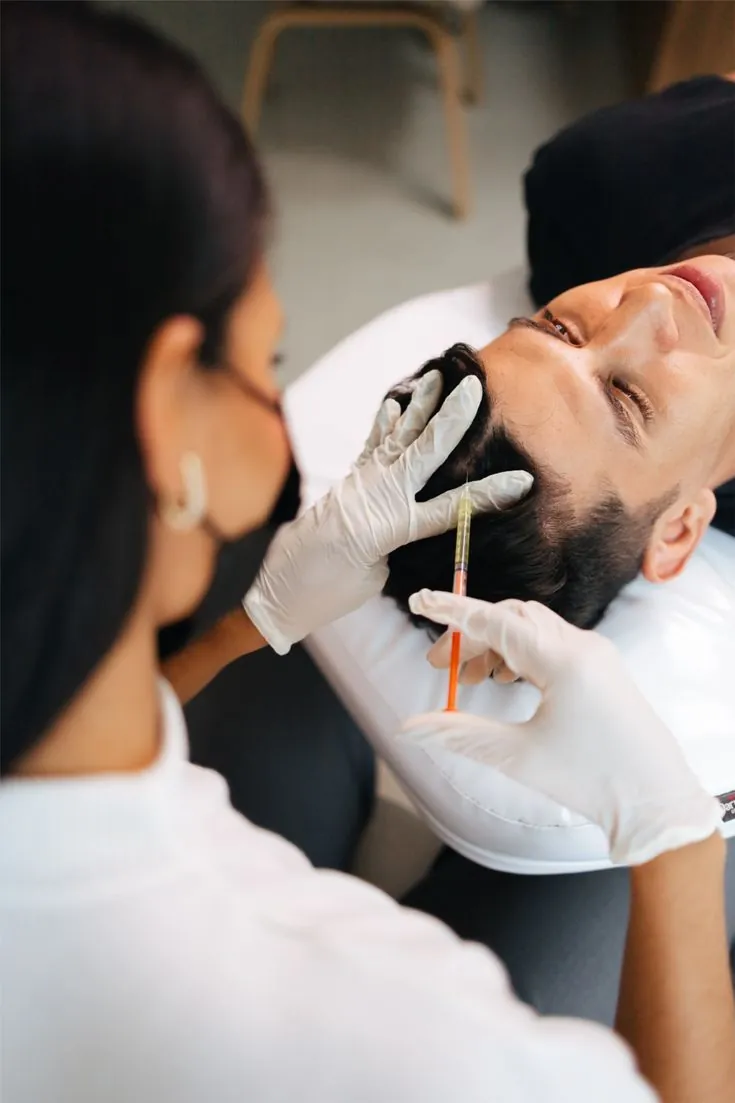 Practitioner performing PRP hair treatment on a man
